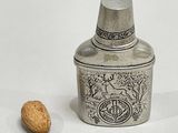 a silver container with a nut in it and a nut in the background