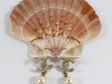 shell with pearl earrings sitting on a white surface next to a seashell