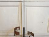 un poteau métallique muni d'une poignée posé sur un plancher en bois