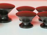 six boutons noirs sur une surface blanche avec un fond rouge