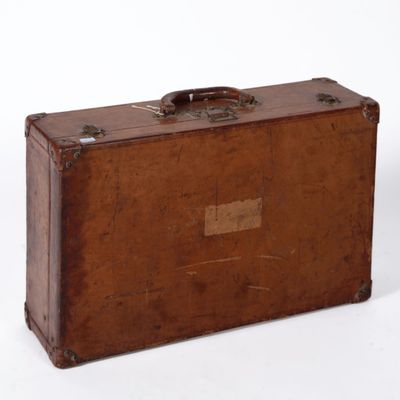 une valise marron posée sur une surface blanche
