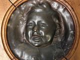 a bronze plaque of a baby in a wooden frame