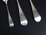 three silver spoons and a fork on a black surface