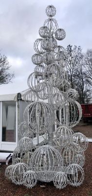a large christmas tree made out of wire on the ground