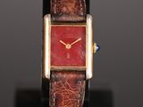 an image of a wrist watch with a red face on a black stand
