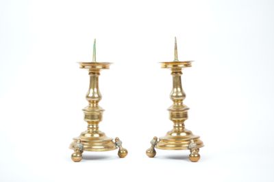 pair of antique brass candlesticks on pedestals on a white background