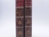 two old books sitting on top of each other on a white surface