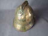 un casque en laiton muni d'une poignée métallique, sur fond gris