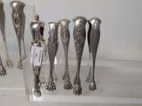 several silver spoons are lined up in a row on a clear shelf
