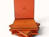 trois boîtes orange sont empilées les unes sur les autres sur une surface blanche