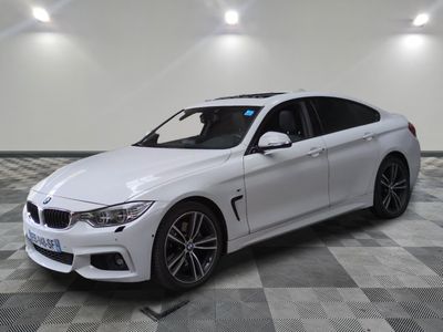 La BMW M4 berline blanche est garée dans une grande pièce.