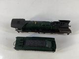 an image of a green train engine sitting next to a black train car