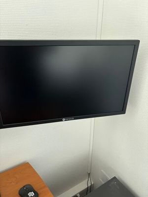 une télévision à écran plat fixée au mur au-dessus d'un bureau