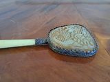 a small mirror on a wooden table with a yellow handle