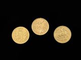 three gold coins are shown against a black background