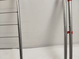 two metal ladders with red handles on a white surface