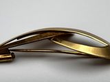 a close up of a gold colored brooch on a white surface