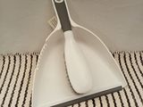 a white dust pan with a black handle on a striped table cloth