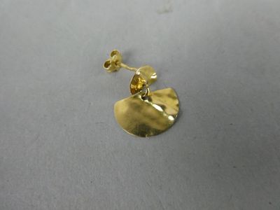 gros plan d'une paire de boucles d'oreilles en or sur une surface blanche