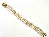 un gros plan sur un bracelet de perles blanches muni d'un fermoir en or