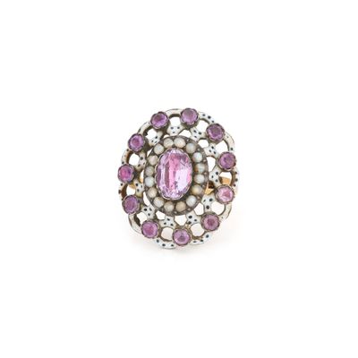 un gros plan d'une bague en pierre rose et perle sur fond blanc