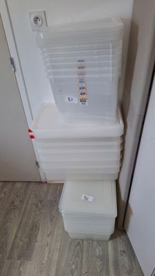 a stack of plastic containers sitting on the floor next to a refrigerator