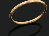 a gold bangle with a textured design on it