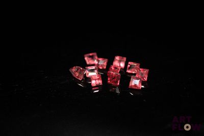 three pieces of red crystal sitting on top of a black surface