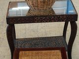un panier en osier posé sur une petite table au plateau en verre