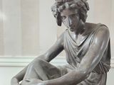 a statue of a woman sitting on a wooden table