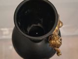 a black vase with a gold decoration on it