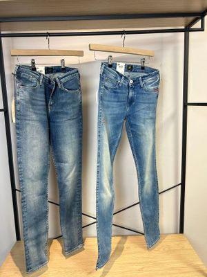 deux paires de jeans suspendues à un portant dans un magasin de vêtements