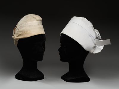 une paire de têtes de mannequins coiffées de chapeaux, exposées sur fond noir