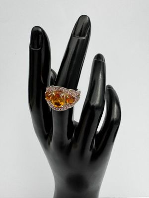 Bague en saphir jaune et diamants, posée sur la main noire d'un mannequin
