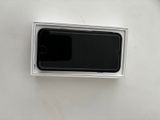 Un iPhone se trouve dans une boîte posée sur une surface blanche