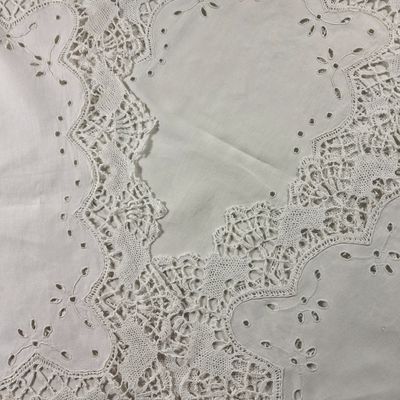 nappe blanche bordée de dentelle et ornée d'un motif floral