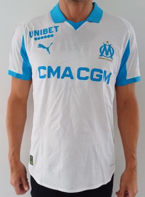 Cet homme porte une chemise blanche et bleue et un pantalon noir.