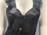 black dress with a large bow on the front and a gold broochet on the back