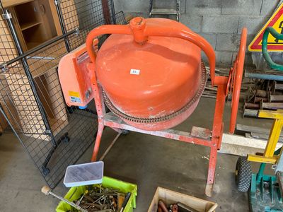 an orange cement mixer sitting in a garage next to other tools