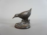 statue représentant un oiseau posé sur un rocher, sur un fond blanc