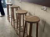 four wooden stools in front of a counter with a cat sitting on top of it