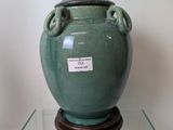 a green vase sitting on top of a glass table