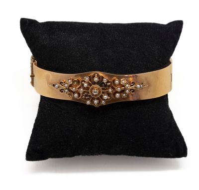 un gros plan sur un oreiller noir sur lequel repose un bracelet doré