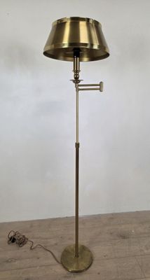 une photo d'un lampadaire en laiton posé sur un parquet
