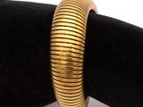 gold plated bracelet on a black velvet cushion on a white background