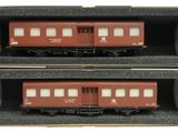 deux trains rouges posés dans une boîte sur une surface blanche
