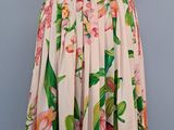 une robe posée sur un pied de mannequin, ornée de fleurs roses et de feuilles vertes