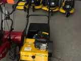 Plusieurs tondeuses à gazon sont alignées dans un garage