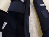 two pairs of knee pads on a wooden floor next to a bottle of water
