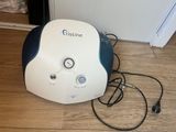 a white and blue machine sitting on the floor next to a wall